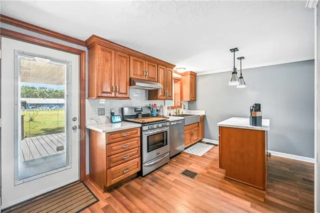 a kitchen with stainless steel appliances granite countertop a stove a sink and a refrigerator