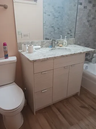 a bathroom with a granite countertop toilet sink and mirror