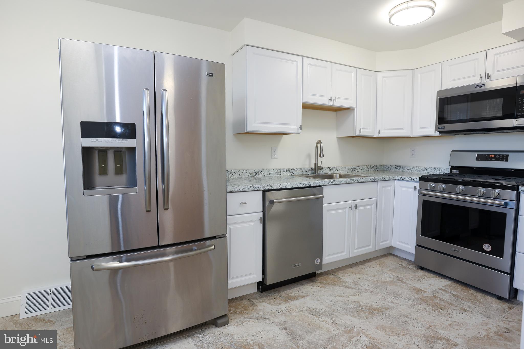 1218 Harshaw Road Brookhaven, PA 19015 - Photo 6 of 21 a kitchen with stainless steel appliances white cabinets white stove a microwave and a refrigerator