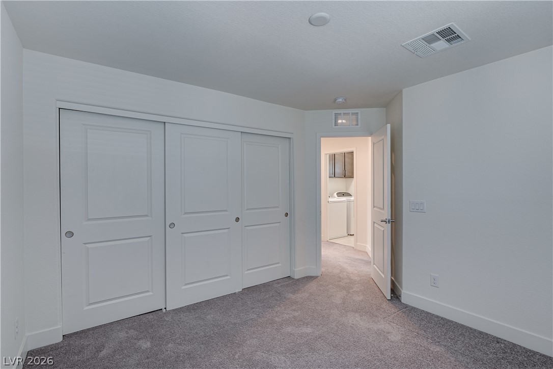 5954 Smith Valley Road Las Vegas, NV 89148 - Photo 21 of 23 Ample closet space and soft carpet define this versatile bedroom, featuring a convenient laundry area just beyond the doorway.