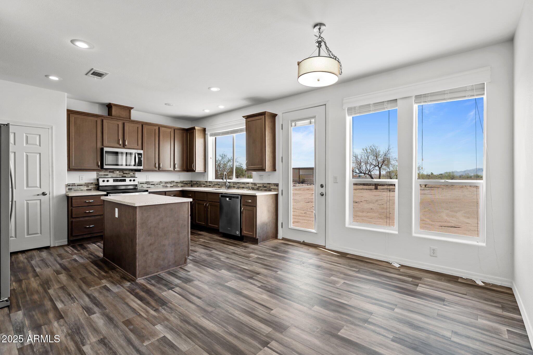 20909 West Bradley Road Wittmann, AZ 85361 - Photo 17 of 37 a kitchen with stainless steel appliances granite countertop a stove a sink dishwasher a refrigerator and white cabinets with wooden floor