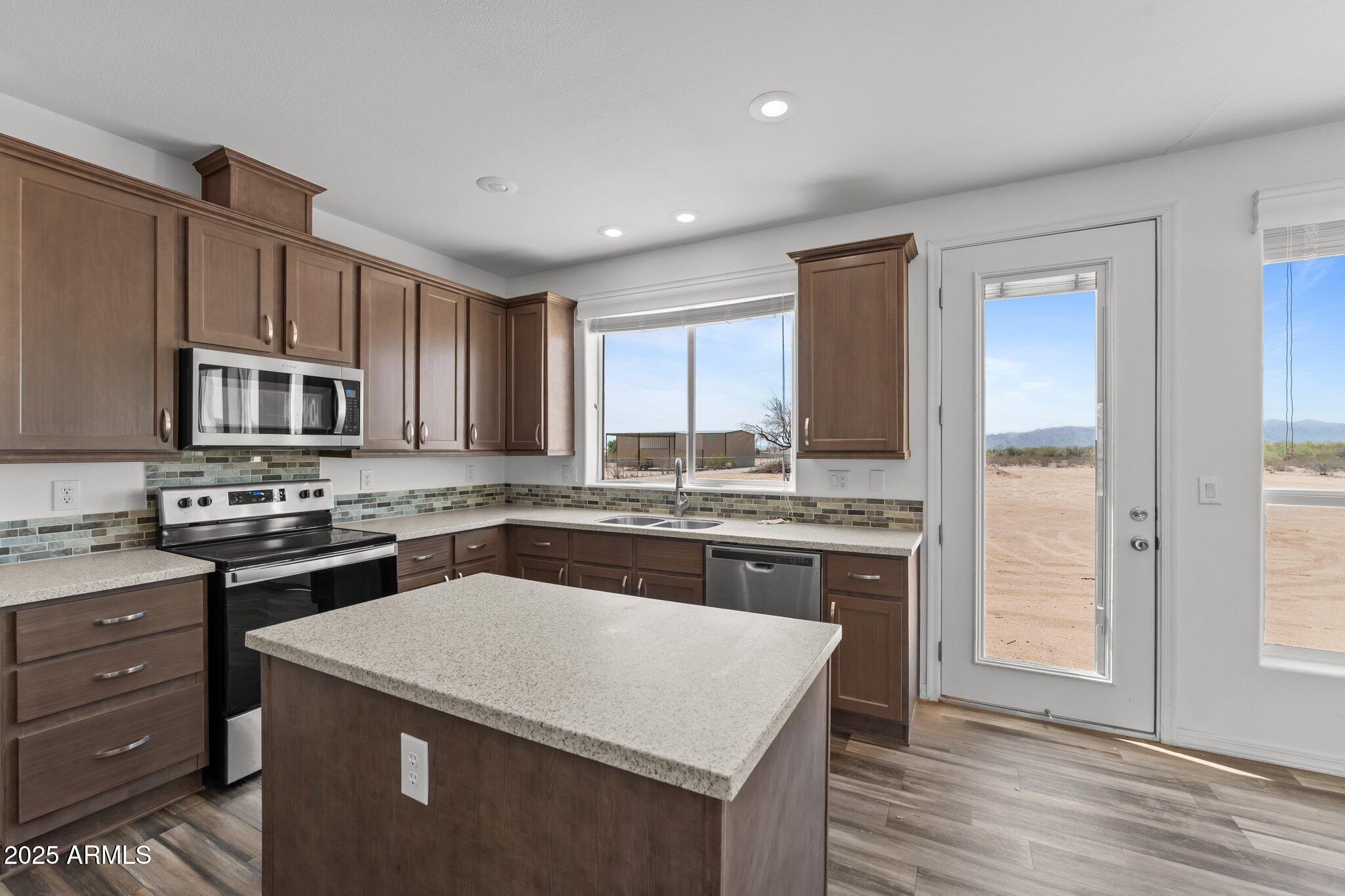 20909 West Bradley Road Wittmann, AZ 85361 - Photo 19 of 37 a kitchen with stainless steel appliances granite countertop a stove top oven a sink dishwasher and a refrigerator with wooden floor