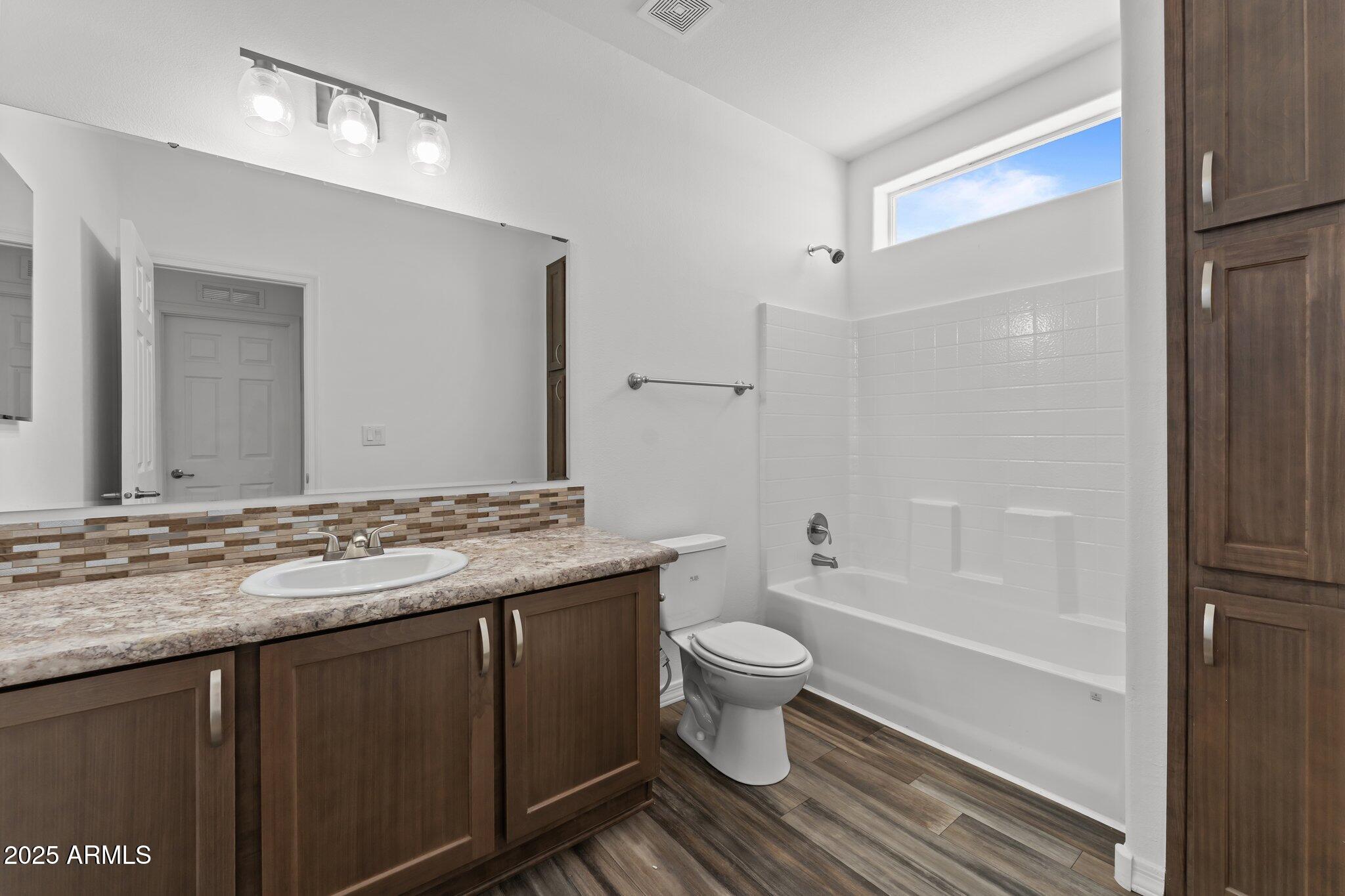 20909 West Bradley Road Wittmann, AZ 85361 - Photo 25 of 37 a bathroom with a granite countertop sink toilet a large mirror a bathtub and shower
