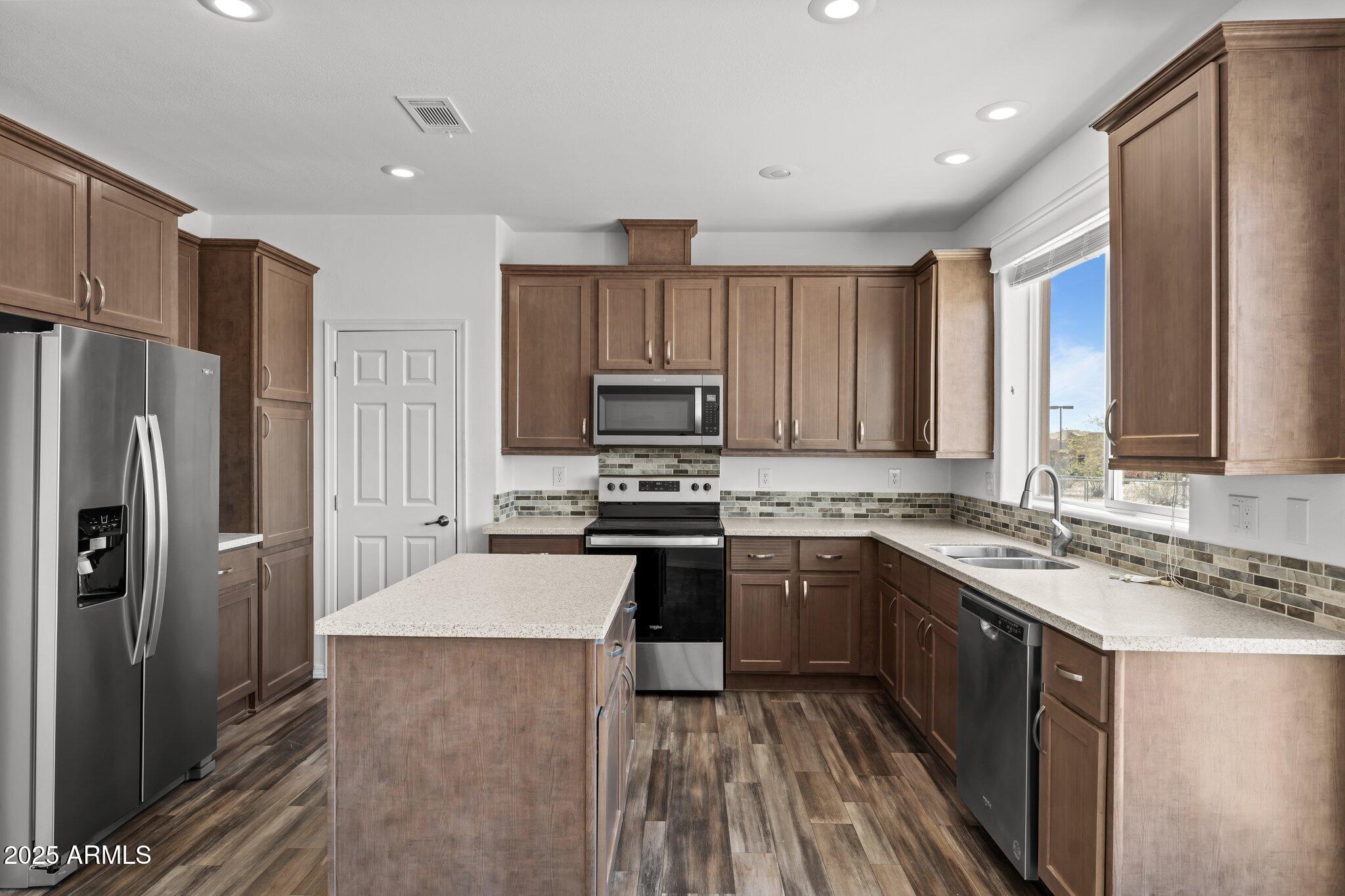 20909 West Bradley Road Wittmann, AZ 85361 - Photo 6 of 37 a kitchen with stainless steel appliances granite countertop a stove top oven a refrigerator a sink and dishwasher