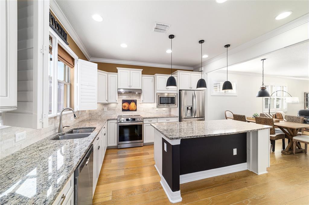 9710 Southwest 76th Lane Road Ocala, FL 34481 - Photo 19 of 45 a large kitchen with stainless steel appliances kitchen island granite countertop a large stove a sink dishwasher and white cabinets with wooden floor