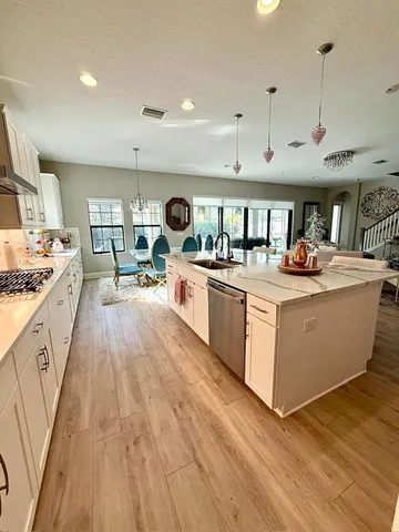 a kitchen with stainless steel appliances a stove a sink a refrigerator and white cabinets with wooden floor
