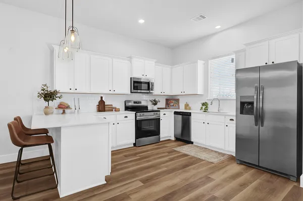a kitchen with granite countertop a stove a sink and a refrigerator