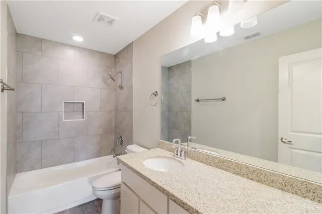 a bathroom with a granite countertop sink a toilet and bathtub