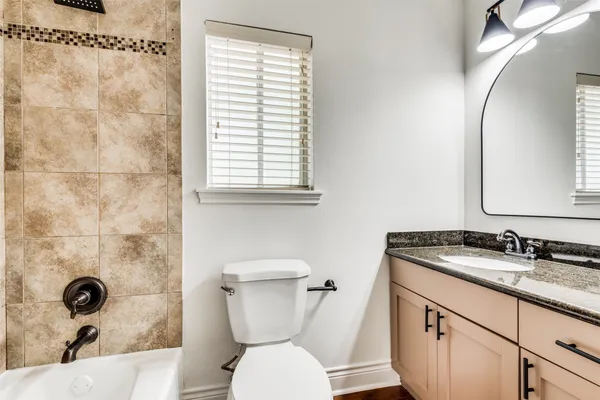 a bathroom with a granite countertop toilet sink and mirror