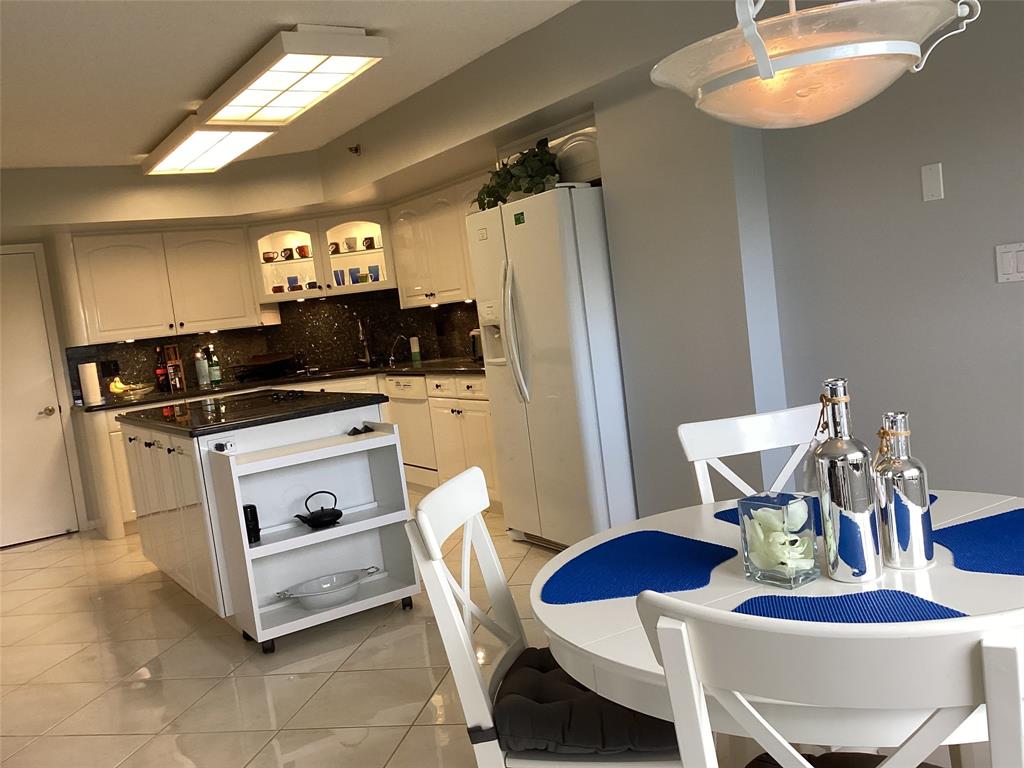 7567 Imperial Drive, Unit 201 Boca Raton, FL 33433 - Photo 12 of 41 a kitchen with stainless steel appliances kitchen island granite countertop a table chairs and a stove