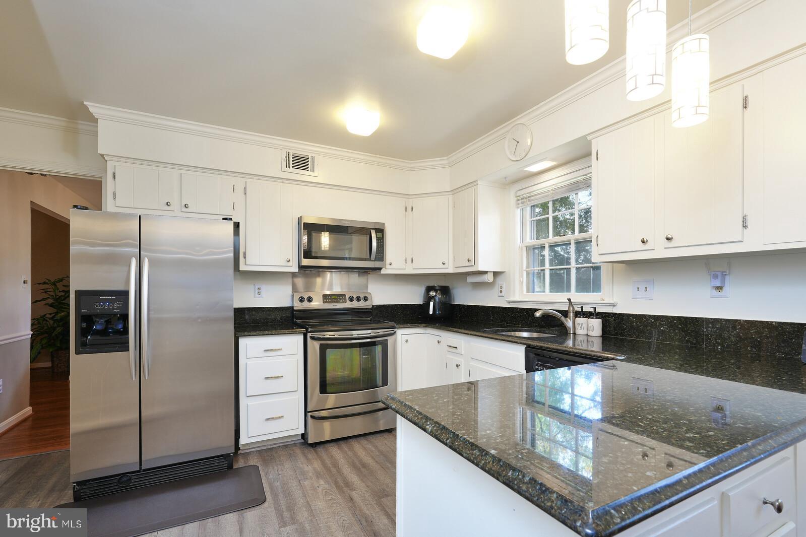 15312 Durant Street Silver Spring, MD 20905 - Photo 23 of 64 a kitchen with stainless steel appliances granite countertop a sink a stove a refrigerator a center island and cabinets