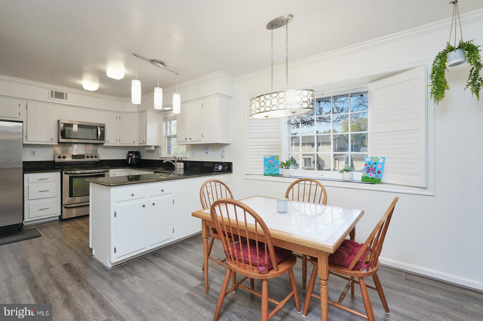15312 Durant Street Silver Spring, MD 20905 - Photo 24 of 64 a kitchen with stainless steel appliances granite countertop a stove a refrigerator a kitchen island a dining table and chairs with wooden floor