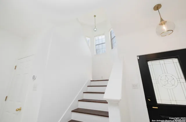 a view of a hallway with stairs and wooden floor