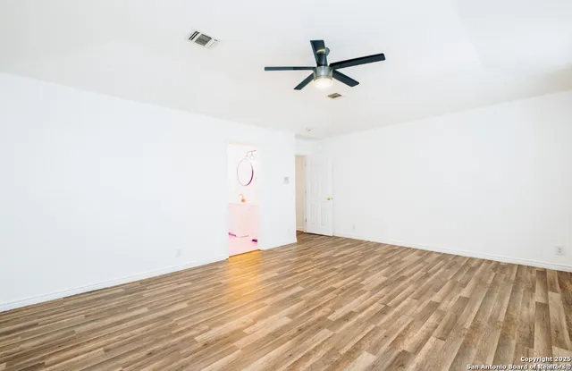 a view of a room with wooden floor and ceiling fan