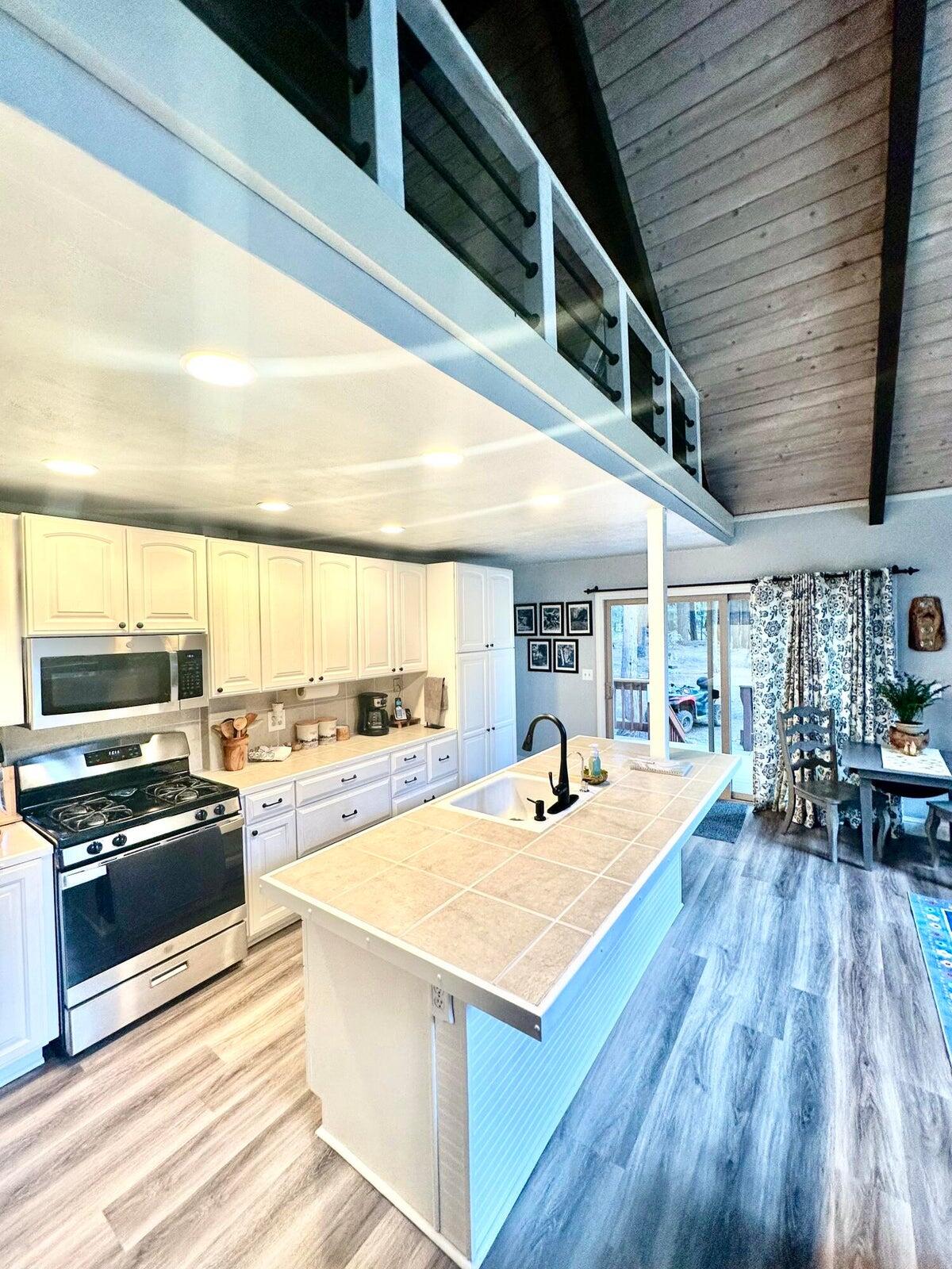 8308 Lost Mill Road Shingletown, CA 96088 - Photo 5 of 11 a view of a kitchen with kitchen island a counter space a sink a stove and wooden floor