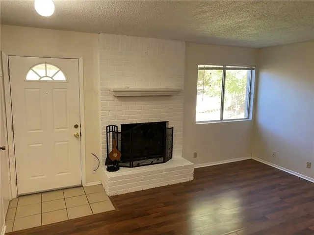 a view of a livingroom with wooden floor and a fireplace