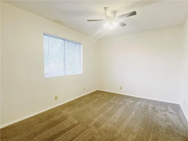 an empty room with a ceiling fan and a window