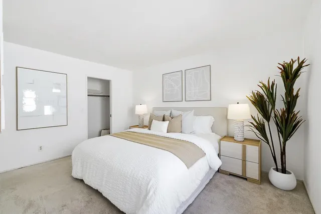 a bedroom with a large bed a potted plant and a large window
