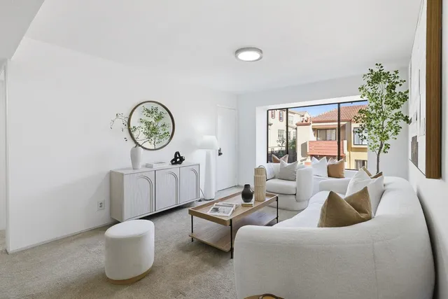 a living room with furniture a large window and a potted plant