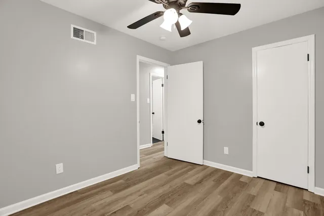 a view of an empty room with window and wooden floor