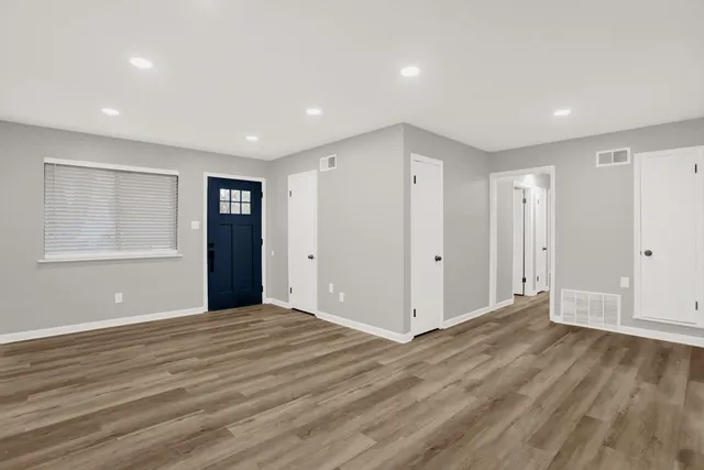 a view of an empty room with wooden floor and windows