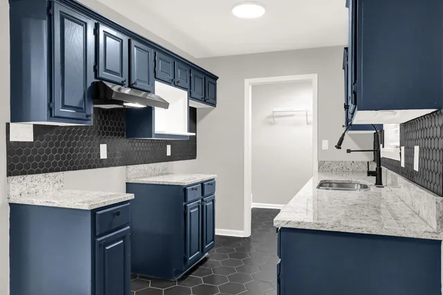 a kitchen with stainless steel appliances granite countertop a stove a sink a refrigerator white cabinets and a window