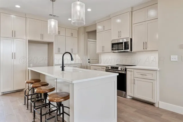 a kitchen with stainless steel appliances a sink a stove a microwave a center island and cabinets