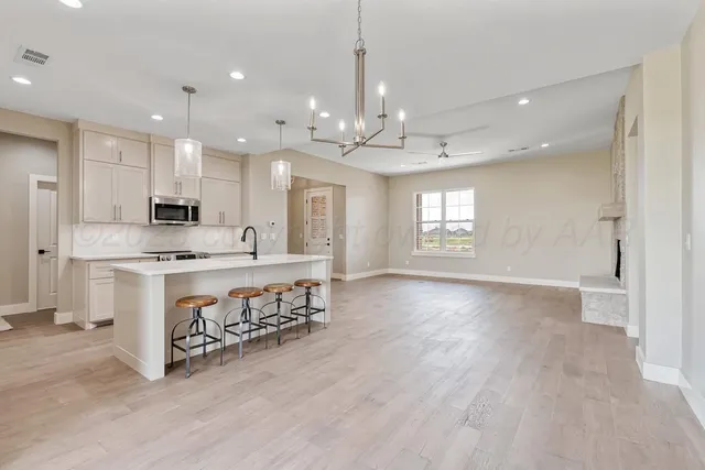 a view of an empty room with kitchen and window