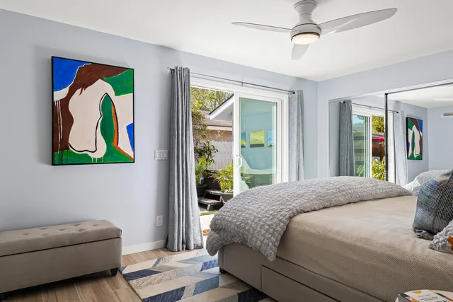 a bedroom with a bed painting on wall and a large window