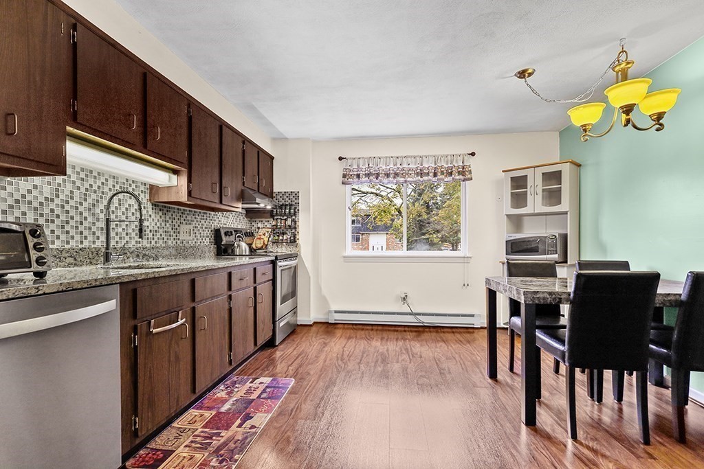 109 Maple Street, Unit E3 Attleboro, MA 02703 - Photo 8 of 18 a kitchen with stainless steel appliances granite countertop a stove top oven a sink dishwasher and cabinets with wooden floor