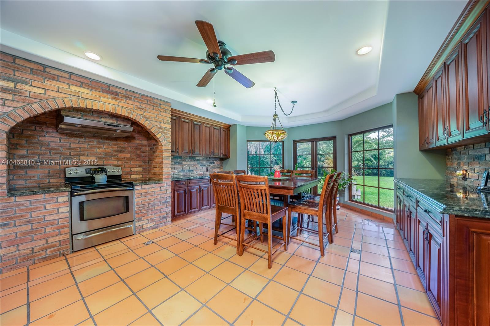 3451 Fox Trail Miramar, FL 33027 - Photo 27 of 33 a kitchen with stainless steel appliances granite countertop a stove top oven a sink a dining table and chairs with wooden floor