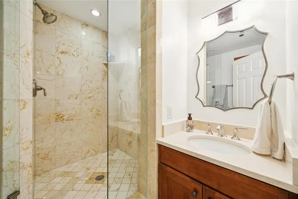 a bathroom with a sink vanity granite shower and a mirror