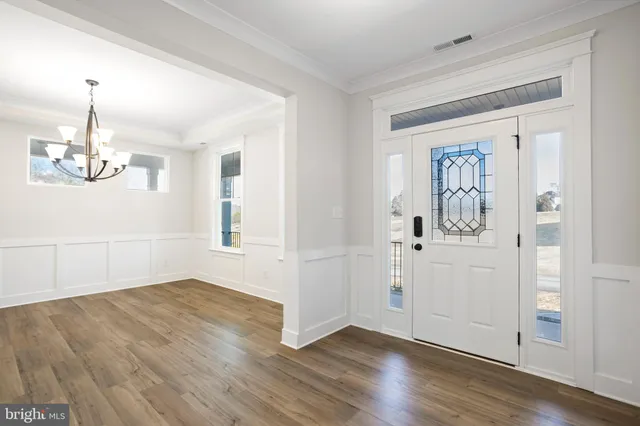 an empty room with wooden floor cabinet and windows