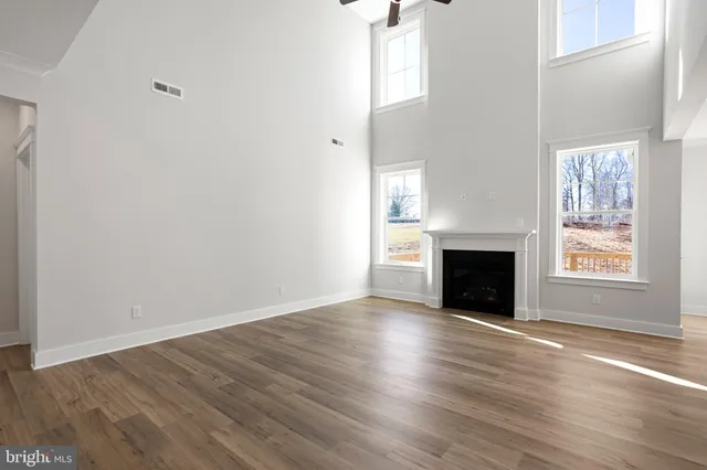 an empty room with wooden floor fireplace and windows