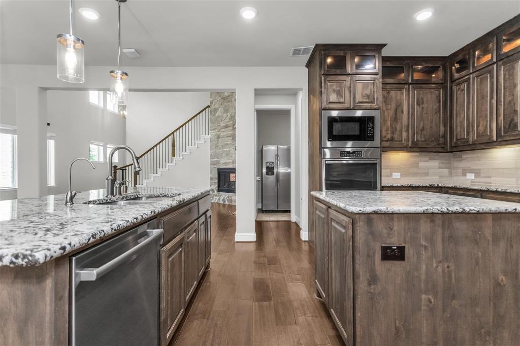 6333 Hall Road Frisco, TX 75034 - Photo 17 of 38 Kitchen featuring wood-finish flooring, granite countertops, stainless steel appliances, pendant lighting, and wood cabinetry
