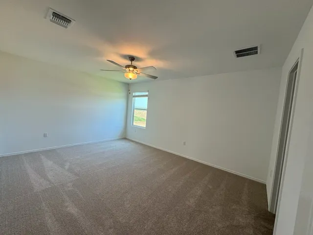 an empty room with a chandelier fan and windows