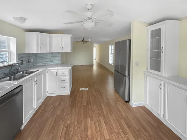 a large kitchen with cabinets wooden floor and stainless steel appliances