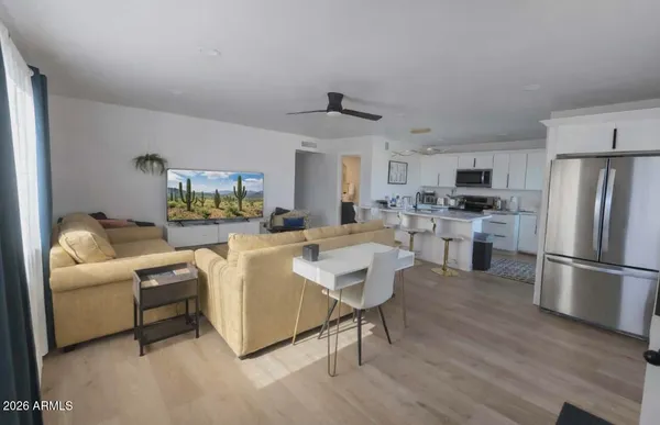 a living room with stainless steel appliances furniture a refrigerator a kitchen and a sink