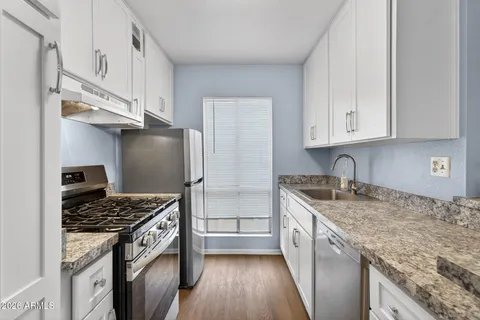 a kitchen with granite countertop a sink stove and refrigerator