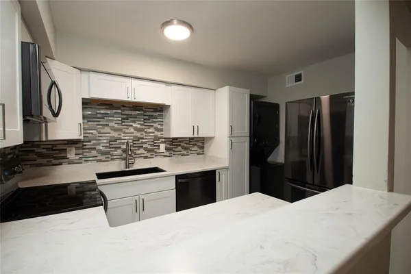 a kitchen with granite countertop a refrigerator and a stove top oven