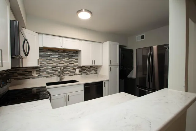 a kitchen with granite countertop a refrigerator and a stove top oven