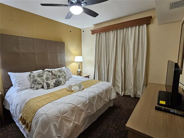 a bedroom with a bed and a flat tv screen on a dresser