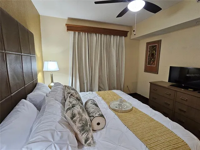 a bedroom with a bed and a flat tv screen on dresser