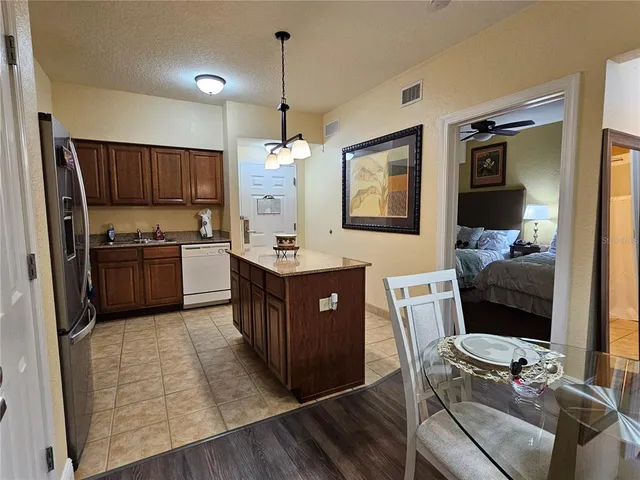 a kitchen with stainless steel appliances granite countertop a sink dishwasher a refrigerator and a oven with wooden floor