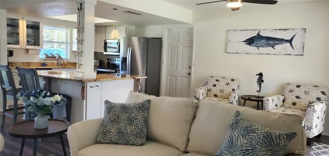 a living room with furniture kitchen view and a chandelier