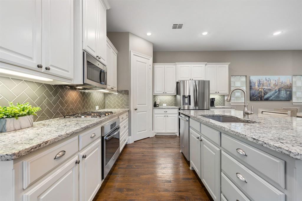 531 Sandy Lane Flower Mound, TX 75022 - Photo 11 of 32 Contemporary kitchen featuring white cabinetry, stainless steel appliances, and a herringbone tile backsplash