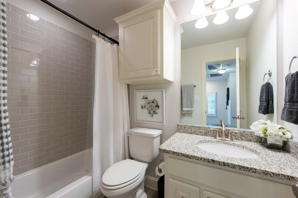 531 Sandy Lane Flower Mound, TX 75022 - Photo 25 of 32 Bathroom featuring a granite countertop vanity with an undermount sink, brushed nickel faucet, light wood-finish cabinetry, and overhead cabinet storage