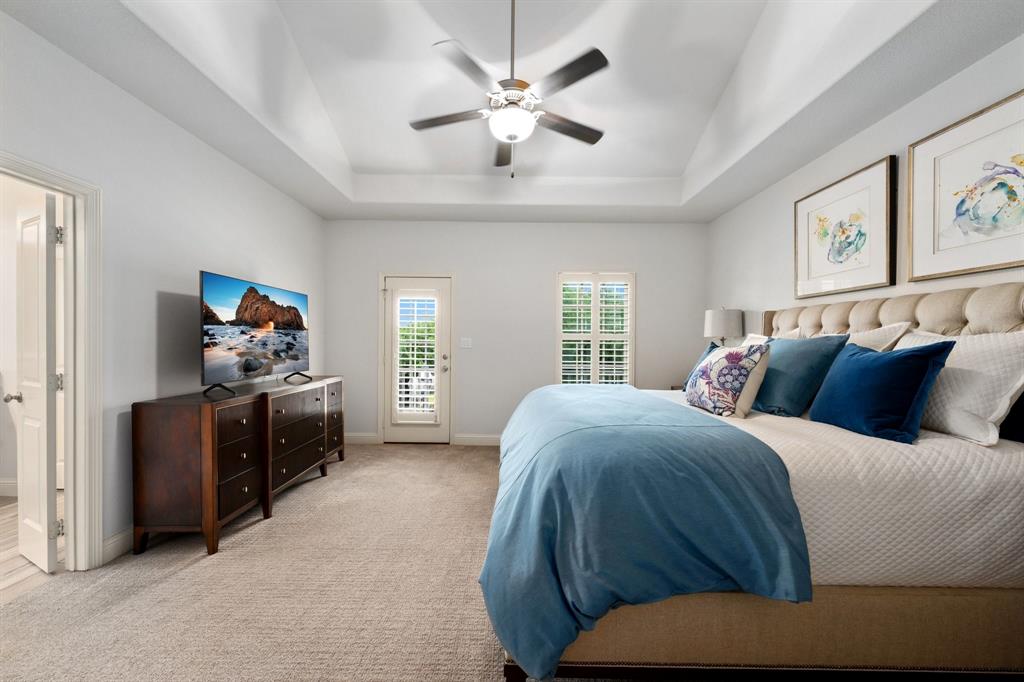 531 Sandy Lane Flower Mound, TX 75022 - Photo 28 of 32 Spacious primary bedroom with tray ceiling with a ceiling fan, and light-colored carpeting