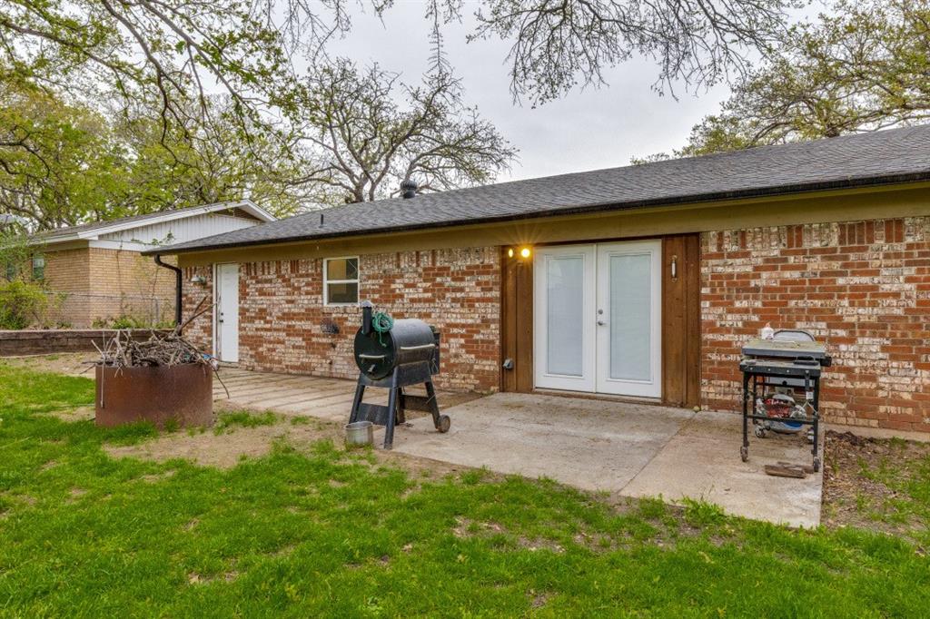 109 North Ash Avenue Azle, TX 76020 - Photo 22 of 25 a view of a backyard with table and chairs potted plants and a large tree