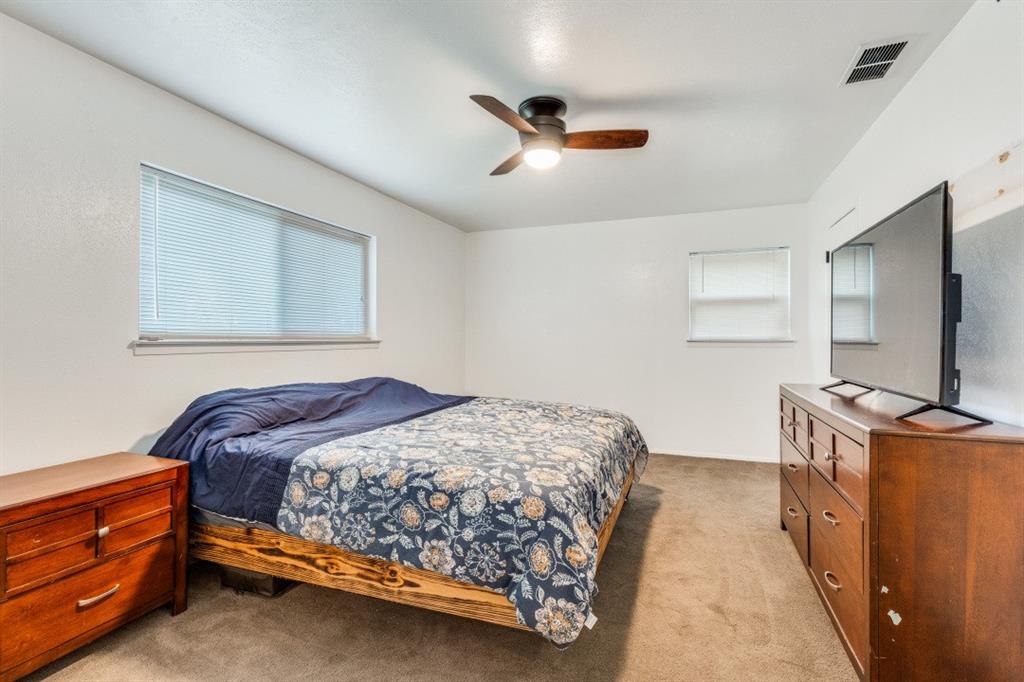 109 North Ash Avenue Azle, TX 76020 - Photo 6 of 25 a bedroom with a bed and a flat tv screen on dresser